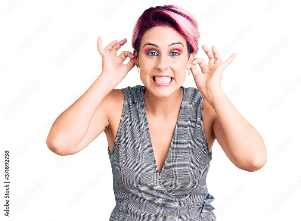 Young beautiful woman with pink hair wearing casual clothes smiling pulling ears with fingers, funny gesture. audition problem Young beautiful woman with pink hair wearing casual clothes smiling pulling ears with fingers, funny gesture. audition problem