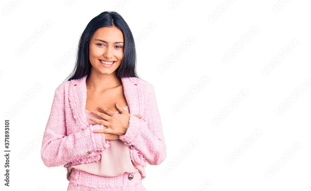 Young beautiful latin girl wearing business clothes smiling with hands on chest with closed eyes and grateful gesture on face. health concept. Young beautiful latin girl wearing business clothes smiling with hands on chest with closed eyes and grateful gesture on face. health concept.