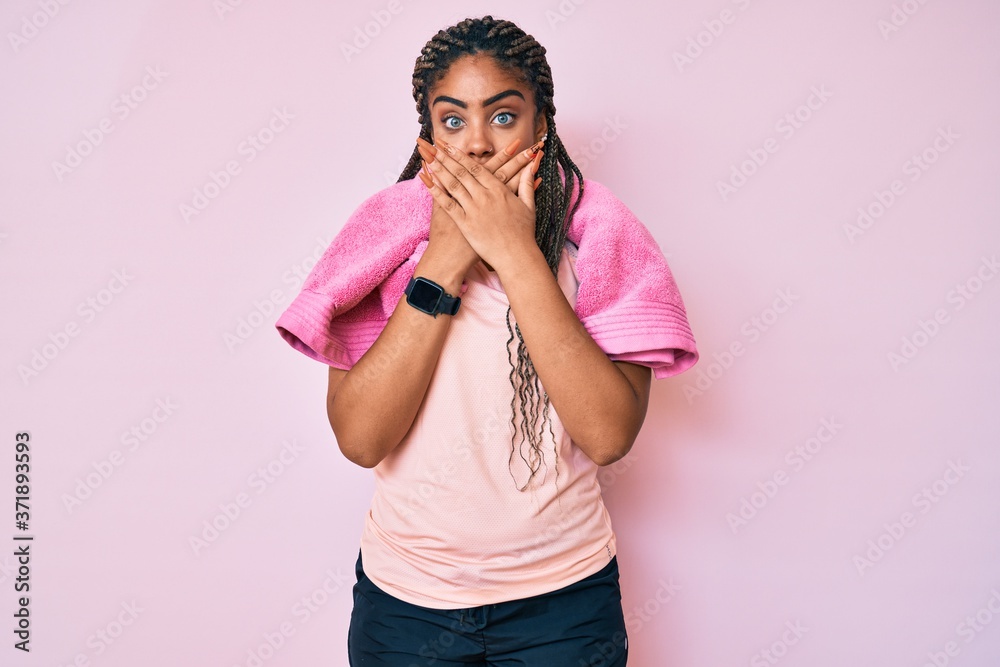 Young african american woman with braids wearing sportswear and towel shocked covering mouth with hands for mistake. secret concept. Young african american woman with braids wearing sportswear and towel shocked covering mouth with hands for mistake. secret concept.