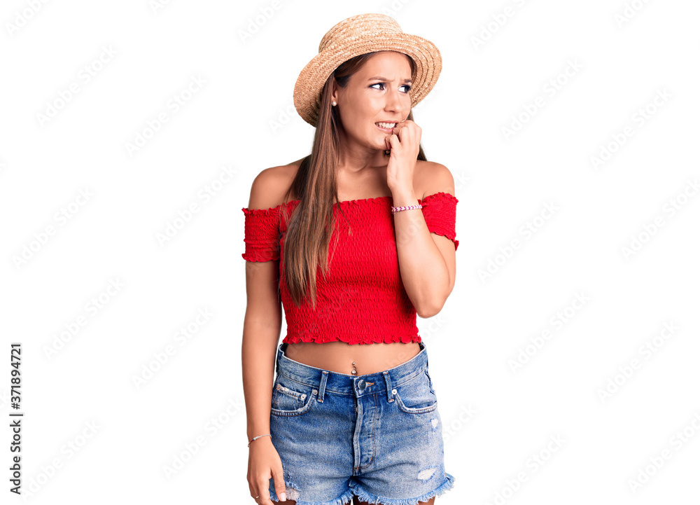 Young beautiful hispanic woman wearing summer hat looking stressed and nervous with hands on mouth biting nails. anxiety problem. Young beautiful hispanic woman wearing summer hat looking stressed and nervous with hands on mouth biting nails. anxiety problem.