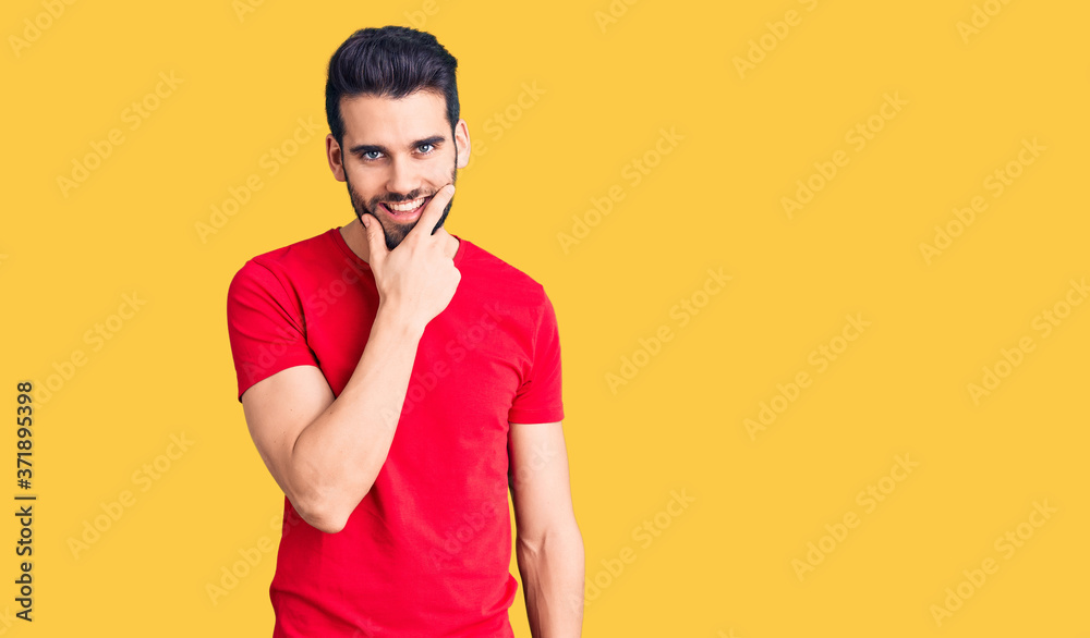 Young handsome man with beard wearing casual t-shirt looking confident at the camera smiling with crossed arms and hand raised on chin. thinking positive. Young handsome man with beard wearing casual t-shirt looking confident at the camera smiling with crossed arms and hand raised on chin. thinking positive.