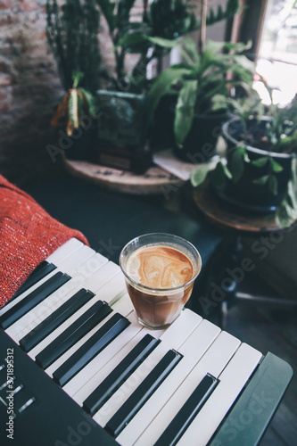 Top view of a cup of latte coffee on Piano keyboard with red fabric.Enjoy coffee and music, Food art creative concept / close up, space for text