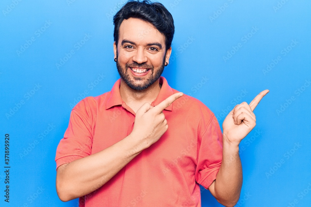 Young hispanic man wearing casual clothes smiling and looking at the camera pointing with two hands and fingers to the side. Young hispanic man wearing casual clothes smiling and looking at the camera pointing with two hands and fingers to the side.