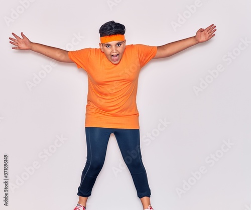 Adorable hispanic kid wearing sportswear smiling happy. Jumping with smile on face over isolated white background © Krakenimages.com