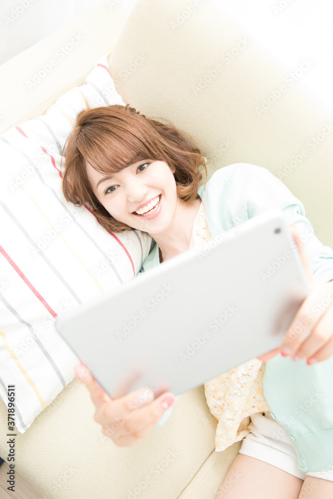 寝転んでタブレットPCを見る女性 寝転んでタブレットPCを見る女性