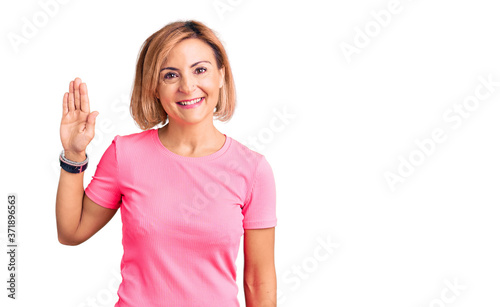 Young blonde woman wearing sportswear waiving saying hello happy and smiling, friendly welcome gesture