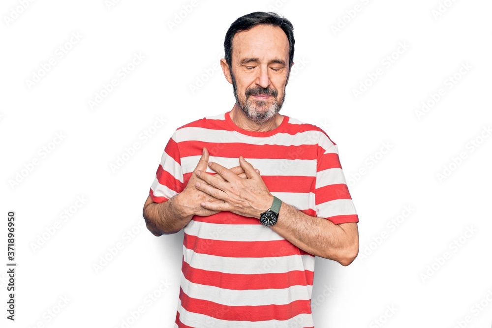 Middle age handsome man wearing striped t-shirt standing over isolated white background smiling with hands on chest, eyes closed with grateful gesture on face. Health concept.