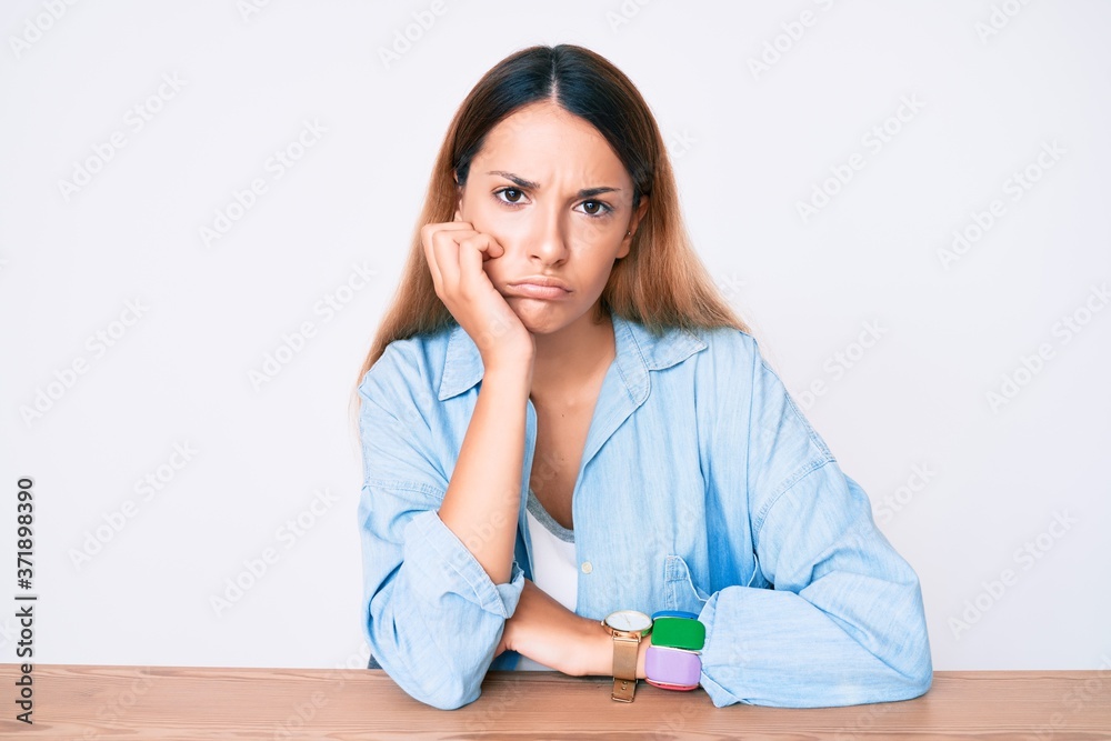 Young brunette woman sitting on the table wearing casual clothes thinking looking tired and bored with depression problems with crossed arms. Young brunette woman sitting on the table wearing casual clothes thinking looking tired and bored with depression problems with crossed arms.