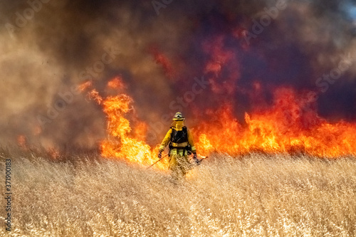 Wildfire raging across grass meadow in California photo