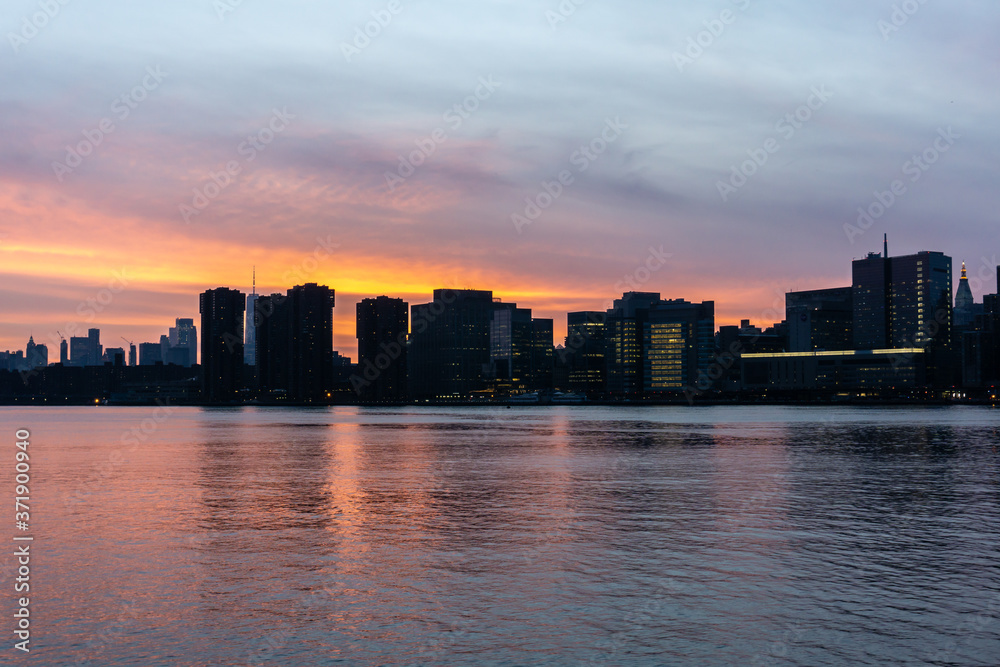 Sunset of Manhattan Skyline in New York City. Silhouette of skyscrapers along East River