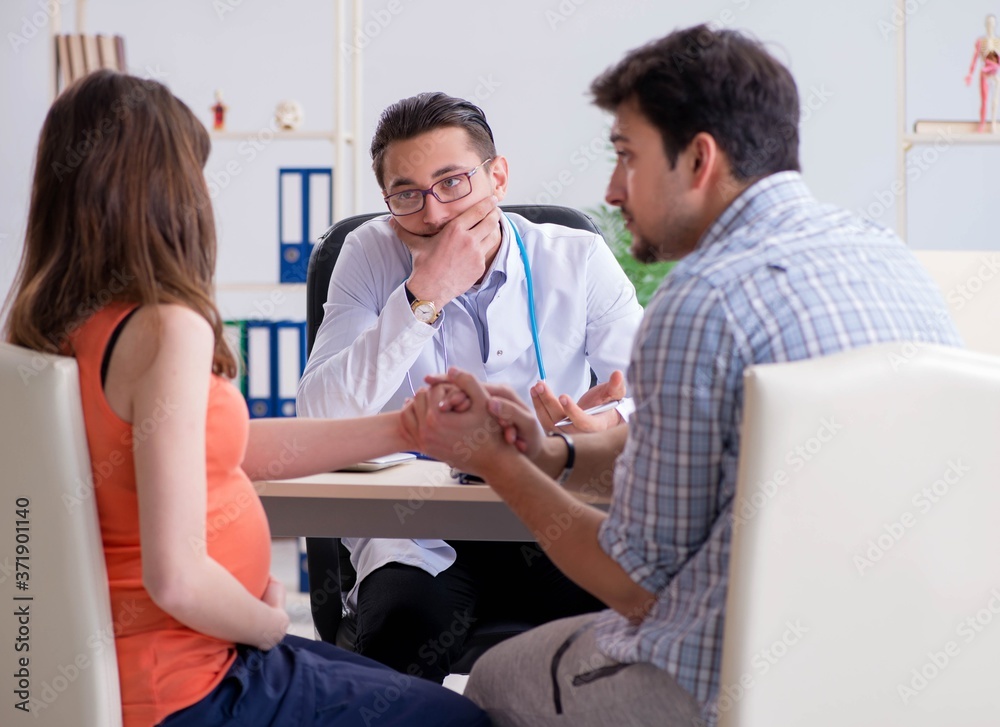 Fototapeta premium Pregnant woman with her husband visiting the doctor in clinic
