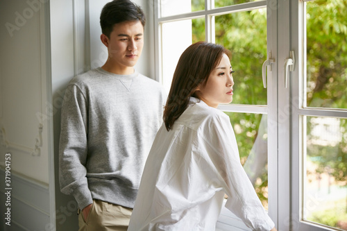 young asian couple standing by window