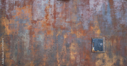 rusty metal surface with small door - worn industrial steampunk background with scratches and bad painted