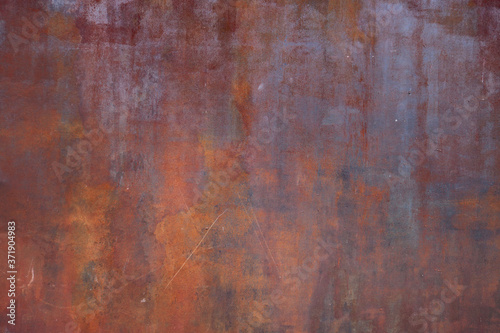 rusty metal surface with red and orange tones - worn irregular steampunk background with scratches for a wallpaper