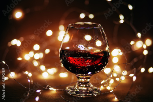 Glass with red wine, backlight, bokeh and blurry orange background.