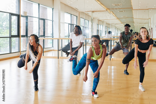 Pretty active young woman showing new movement to young people in dance class