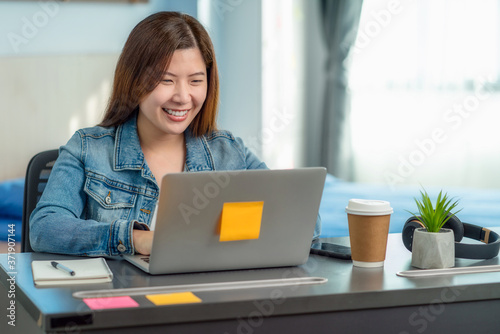Asian business woman using technology laptop and working from home in indoor bedroom of house by video conference call,startups and business owner,social distance and covid outbreak new normal concept © THANANIT