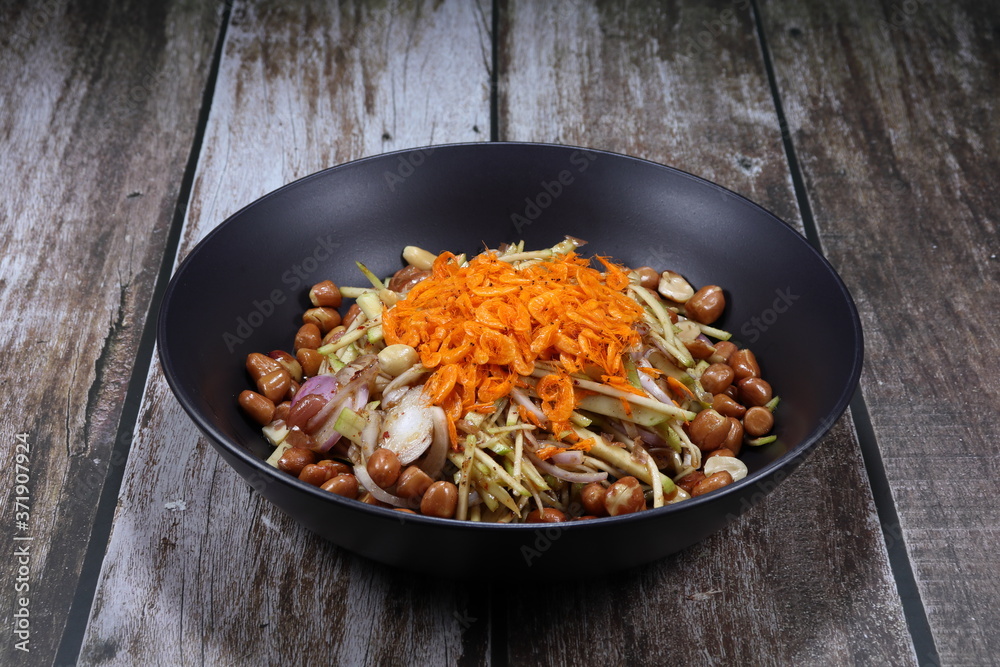 Traditional spicy sliced fresh mango with shallot, chilly, roasted peanut and dried shrimp seasoning with sweet and sour sauce. Famous appetizer and side dish in Asia restaurant. Low fat and diet menu