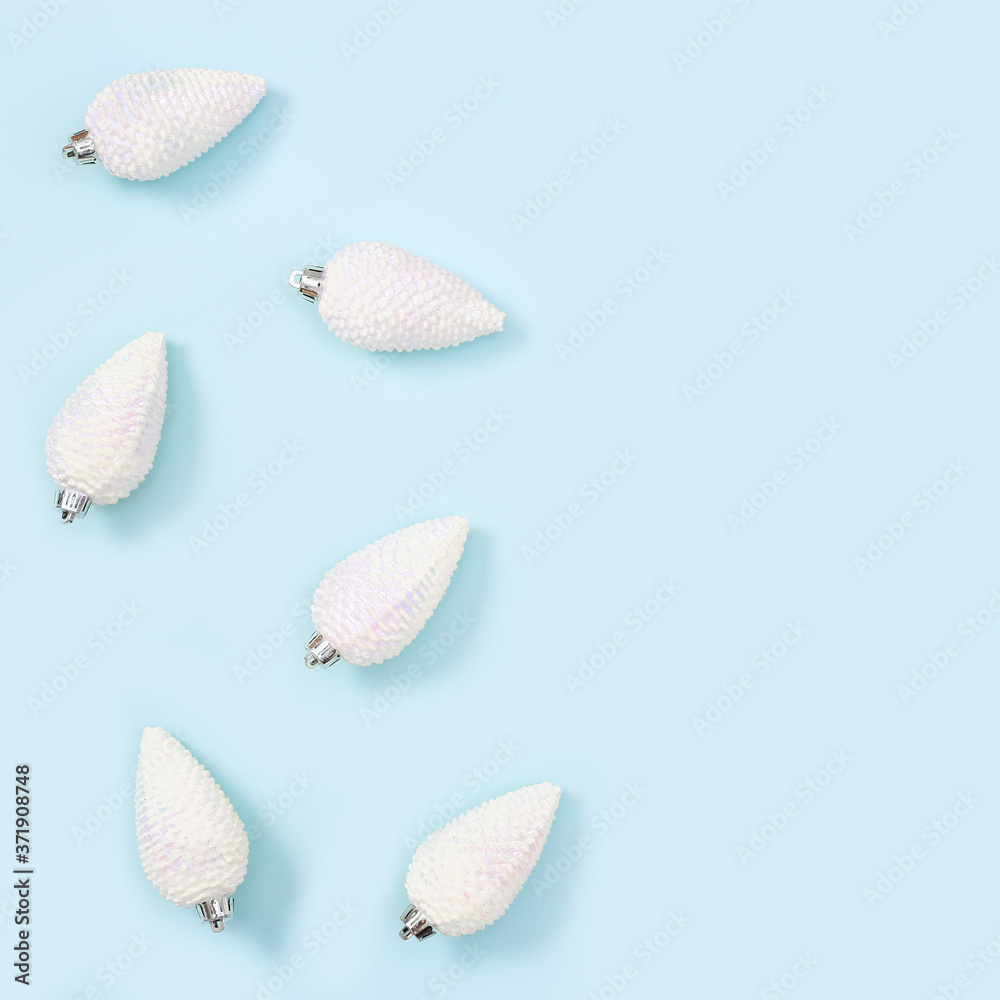 White Christmas toys in shape of pine cones, New Year toys on blue background.
