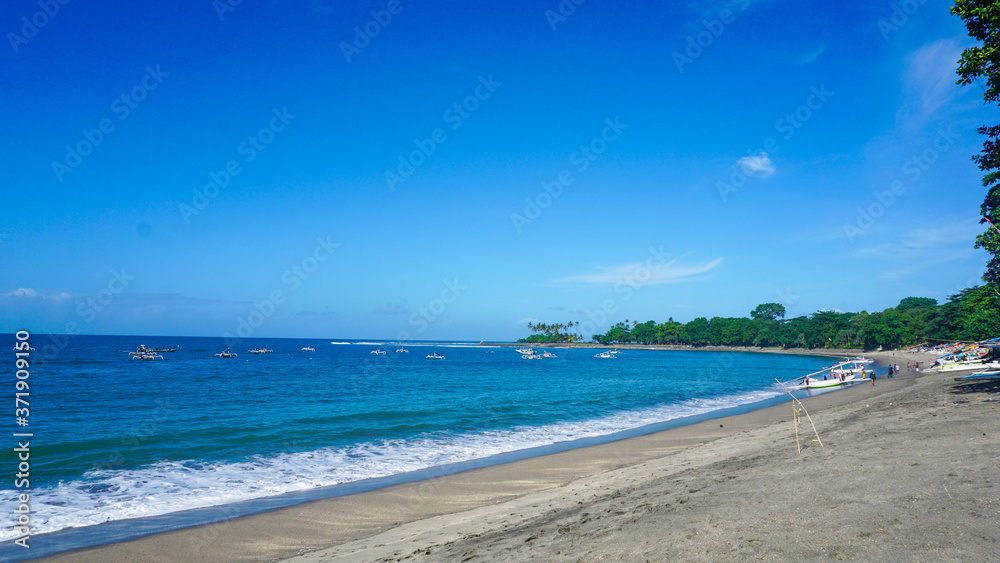 Sandy beach with calm ocean waves in Bali with clear blue sky