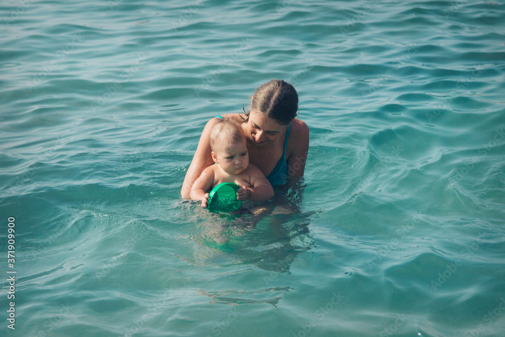 A young mother and daughter swim in the sea. swimming training.