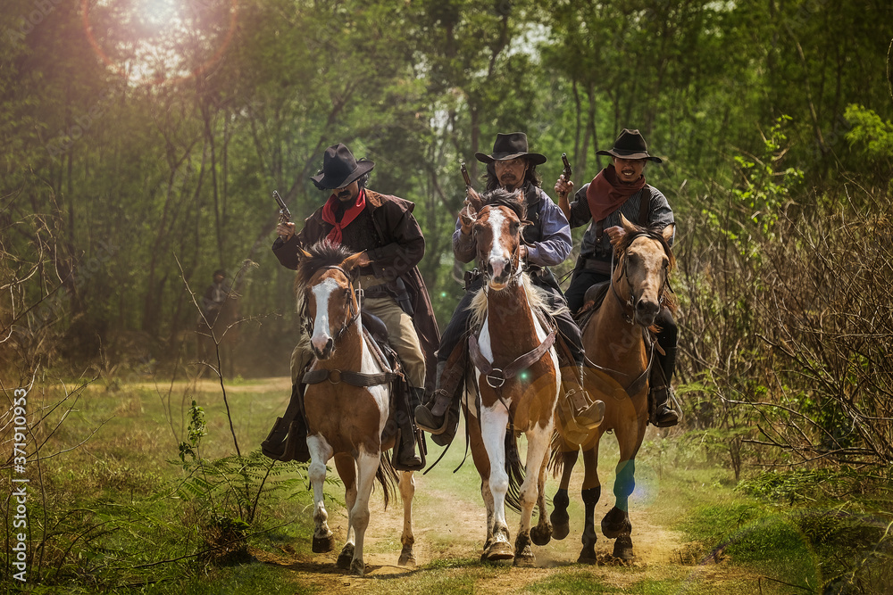 Asian Man Cowboy travels on horseback and carries a gun at sunset. Asian Man Cowboy travels on horseback and carries a gun at sunset.