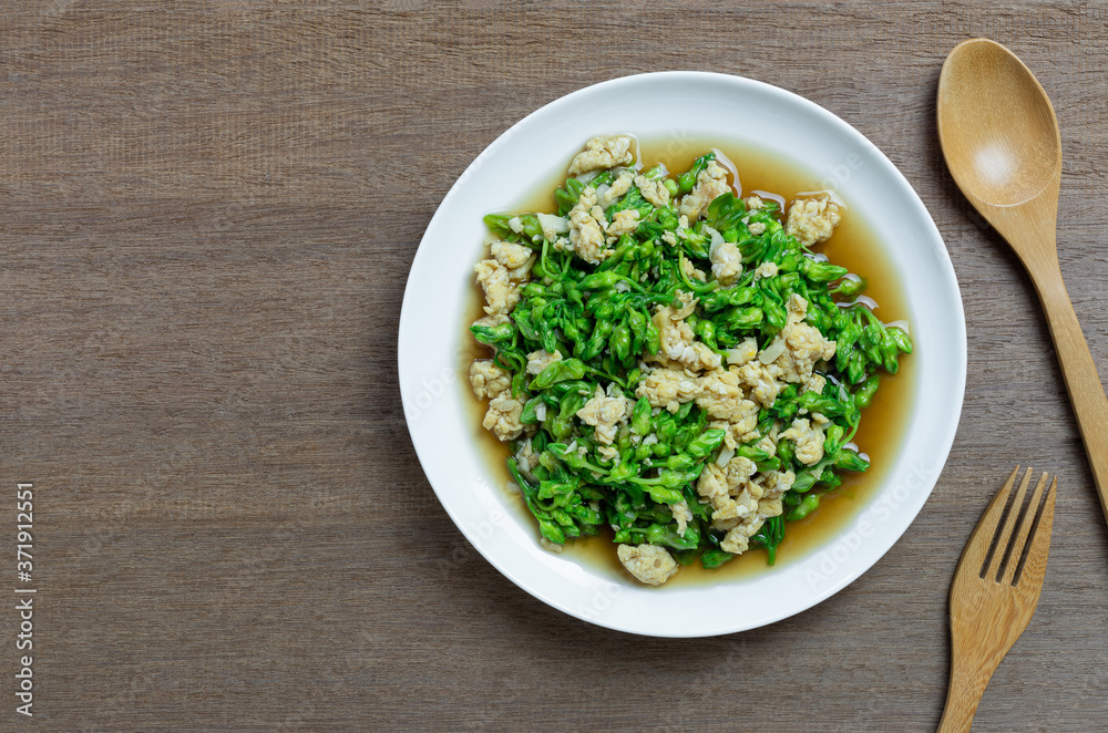 top view of stir fried cowslip creeper with egg in a ceramic dish on wooden table. homemade style healthy food concept. top view of stir fried cowslip creeper with egg in a ceramic dish on wooden table. homemade style healthy food concept.