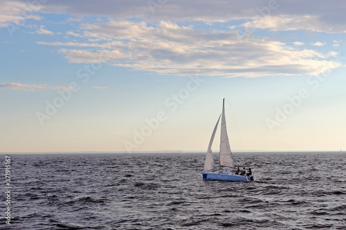 A sailing boat sails on the sea. Open sails. Active sport. Sailing on a yacht.