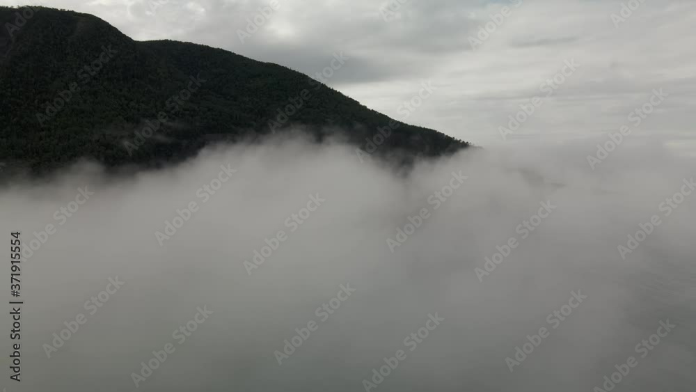 Thick White Clouds Covered The Chic-Choc Mountains And Village By The Gaspe Peninsula In Quebec, Canada. - aerial drone Thick White Clouds Covered The Chic-Choc Mountains And Village By The Gaspe Peninsula In Quebec, Canada. - aerial drone