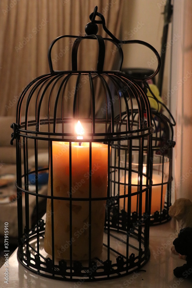 Lighted candle in a black cage
