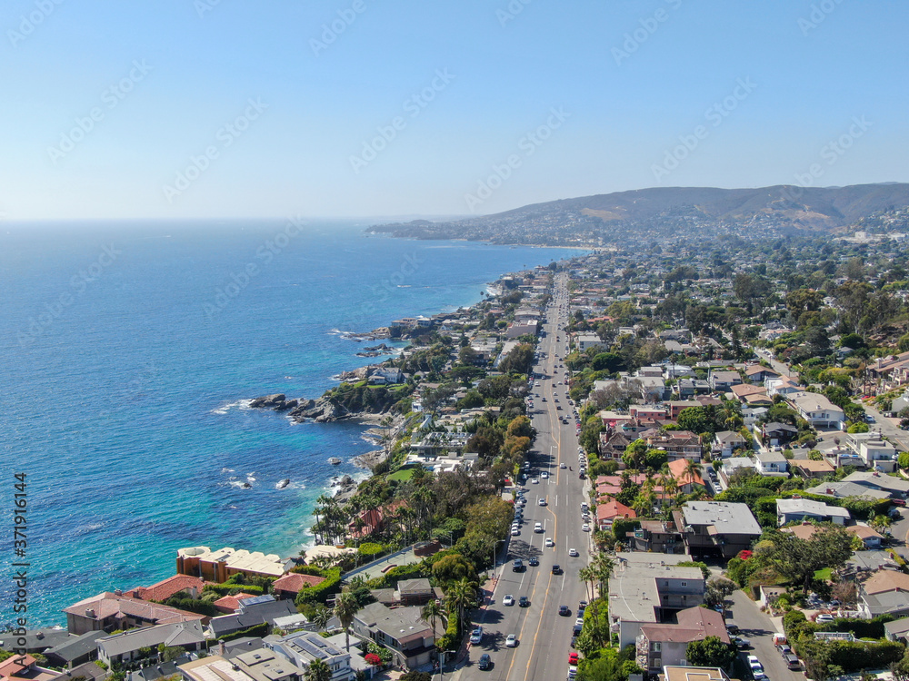 Aerial view of main road crossing Laguna Beach coastline town with houses on the hills and pacific ocean, Southern California Coastline, USA