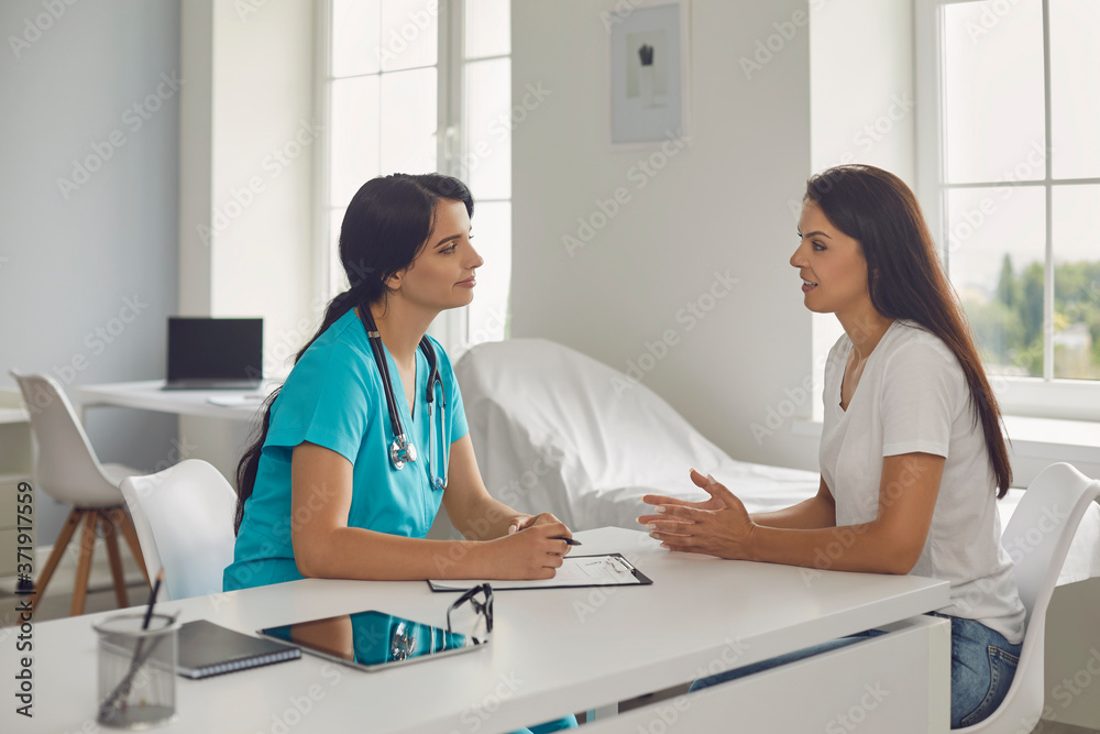 Woman nurse or doctor listening to patients complaints during visit in clinic