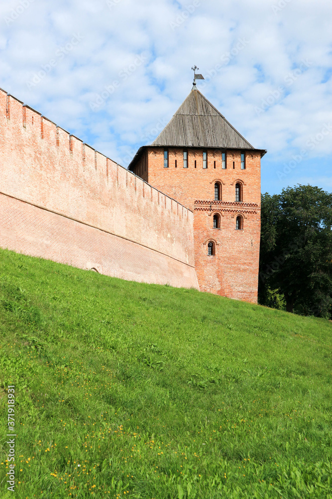 View to Vladimir tower and wall of the Velikiy (Great) Novgorod citadel (kremlin, detinets) in Russia under blue summer sky in the morning View to Vladimir tower and wall of the Velikiy (Great) Novgorod citadel (kremlin, detinets) in Russia under blue summer sky in the morning
