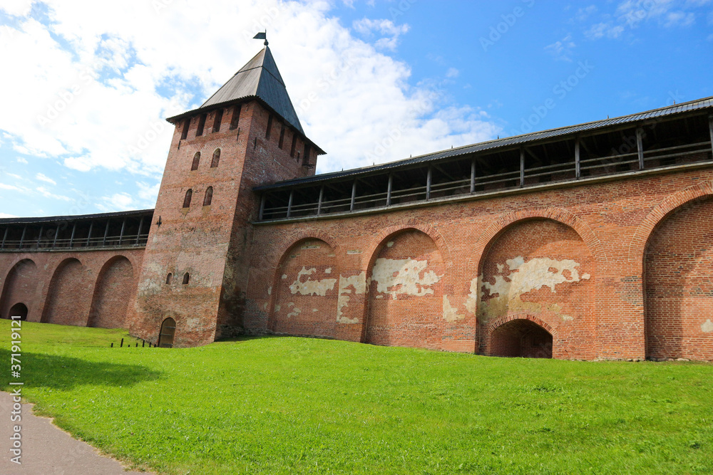 View from the courtyard of Velikiy (Great) Novgorod citadel (kremlin, detinets) to the walls and towers under blue summer sky with clouds in the morning