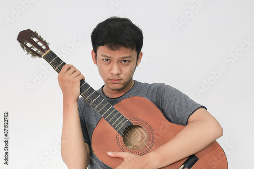 Young Asian musician who is sad by hugging his guitar
