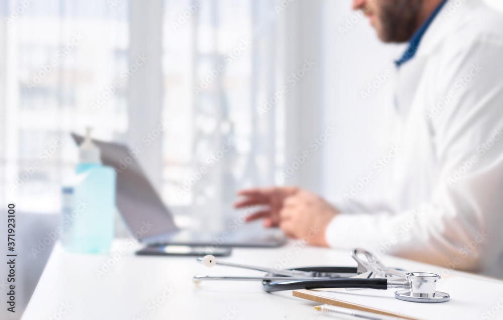 Stethoscope and clip board on the doctors desk in the background, the doctor conducts an online patient consultation using laptop. Online medicine concept Stethoscope and clip board on the doctors desk in the background, the doctor conducts an online patient consultation using laptop. Online medicine concept
