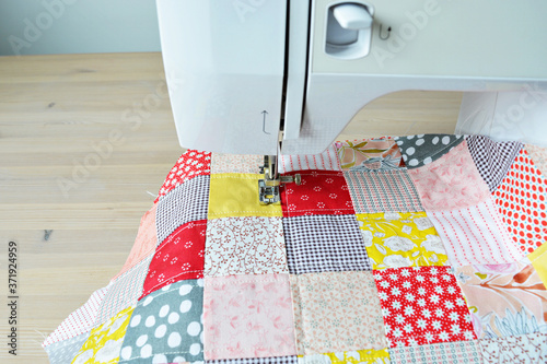 Quilting process: quilt and sewing machine on wooden desk