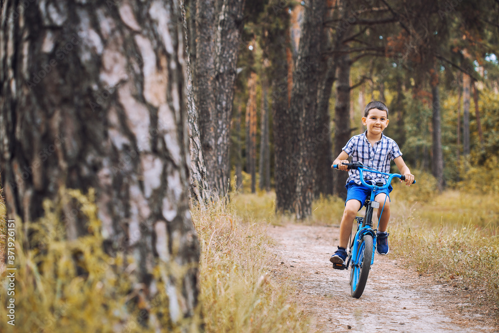 Funny boy cyclist rides in the sunny forest on a bike. Adventure travel. Funny boy cyclist rides in the sunny forest on a bike. Adventure travel.