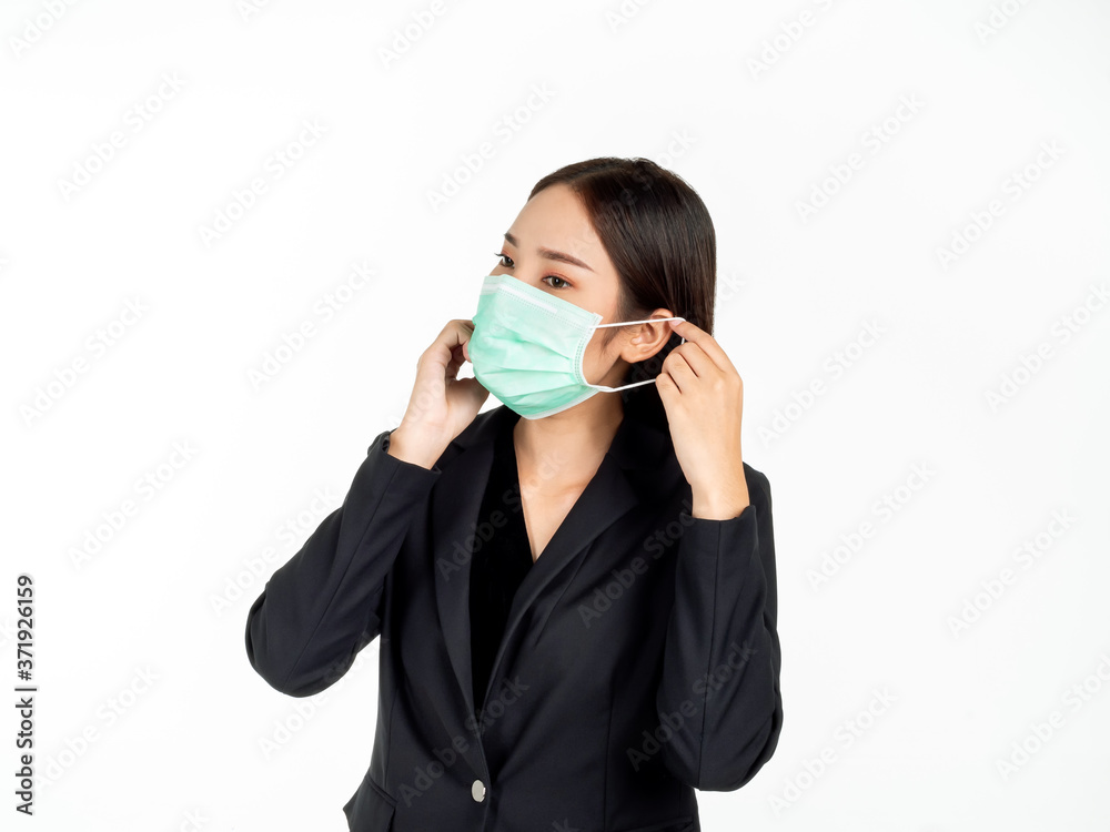 A confident beautiful young Asian business woman wearing green medical face mask and black suit. A confident beautiful young Asian business woman wearing green medical face mask and black suit.