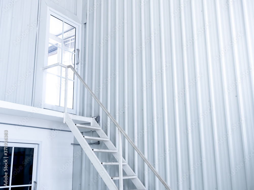 Fototapeta premium Inside white modern cutting-edge shipping container construction office building with white iron staircase leads up to the glass door on the upper floor.