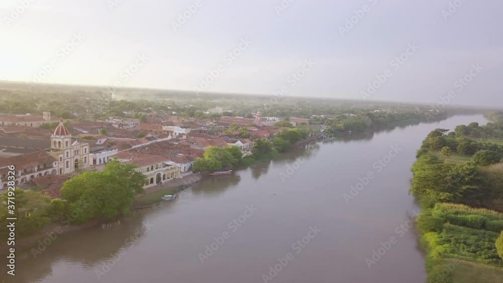 Santa Cruz de Mompox in Colombia. Aerial Drone pan over the river towards the historic centre of town during sunset. Santa Cruz de Mompox in Colombia. Aerial Drone pan over the river towards the historic centre of town during sunset.