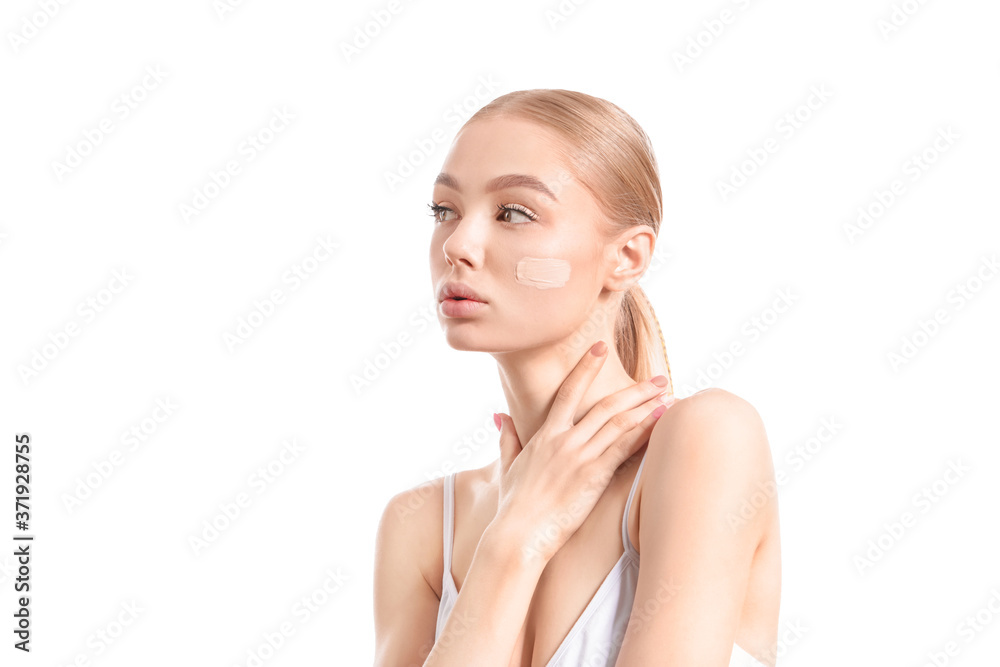 Beautiful young woman with foundation on her face against white background