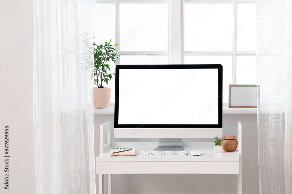 Modern PC monitor on table near window Modern PC monitor on table near window