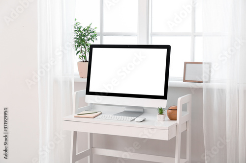 Modern PC monitor on table near window © Pixel-Shot