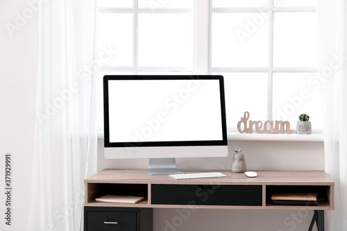 Modern PC monitor on table near window © Pixel-Shot