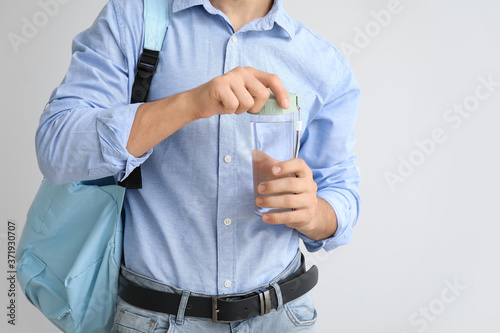 Young man with bottle of water on light background