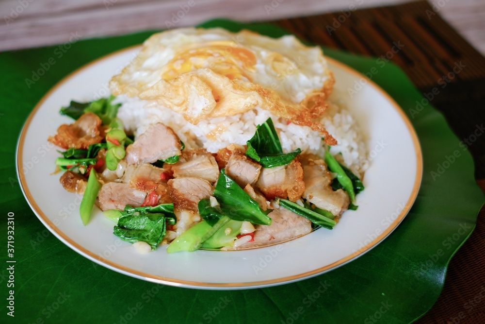 Stir-fried kale vegetable oyster sauce with crispy pork with fried egg top on rice and the plate. Stir-fried kale vegetable oyster sauce with crispy pork with fried egg top on rice and the plate.