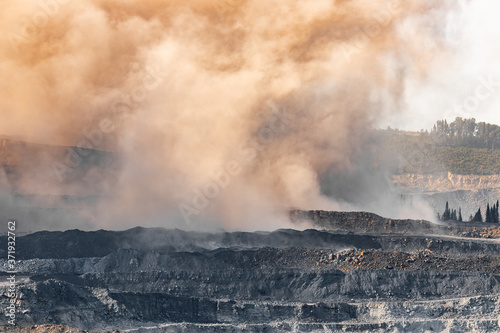 Explosive works on open pit coal mine industry. Dust and puffs of smoke in sky, blasted soil