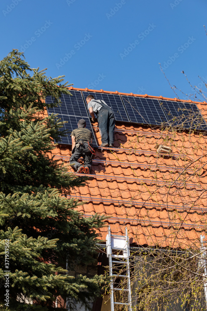 Fototapeta premium Workers installing solar electric panels on a house roof in Ochojno. Poland
