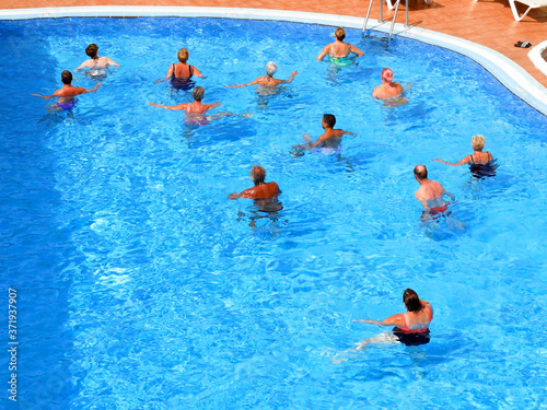 People doing aqua gym in swimming pool in resort, tourism in coronavirus time concept photo